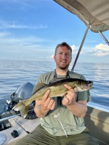 Man holds a fish on a boat.