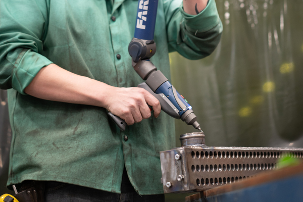 An L&M Radiator employee uses a Faro Arm to proof and prove a built design.