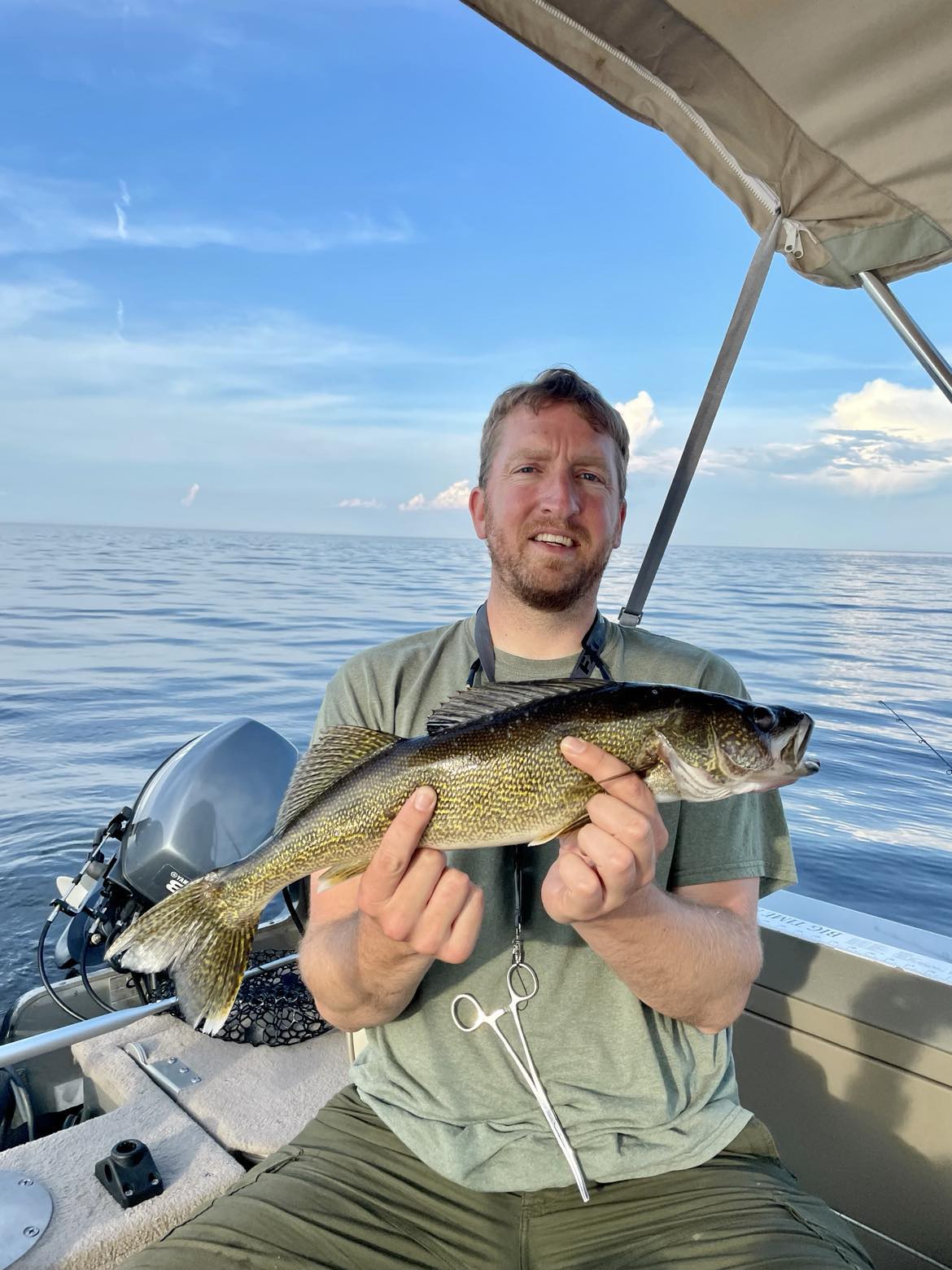 Man holds a fish on a boat.