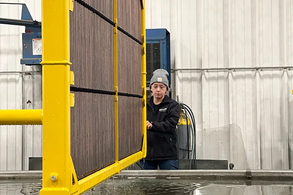 A Mesabi crew-member submerges a Mesabi radiator into a large test tank to check for potential leaks